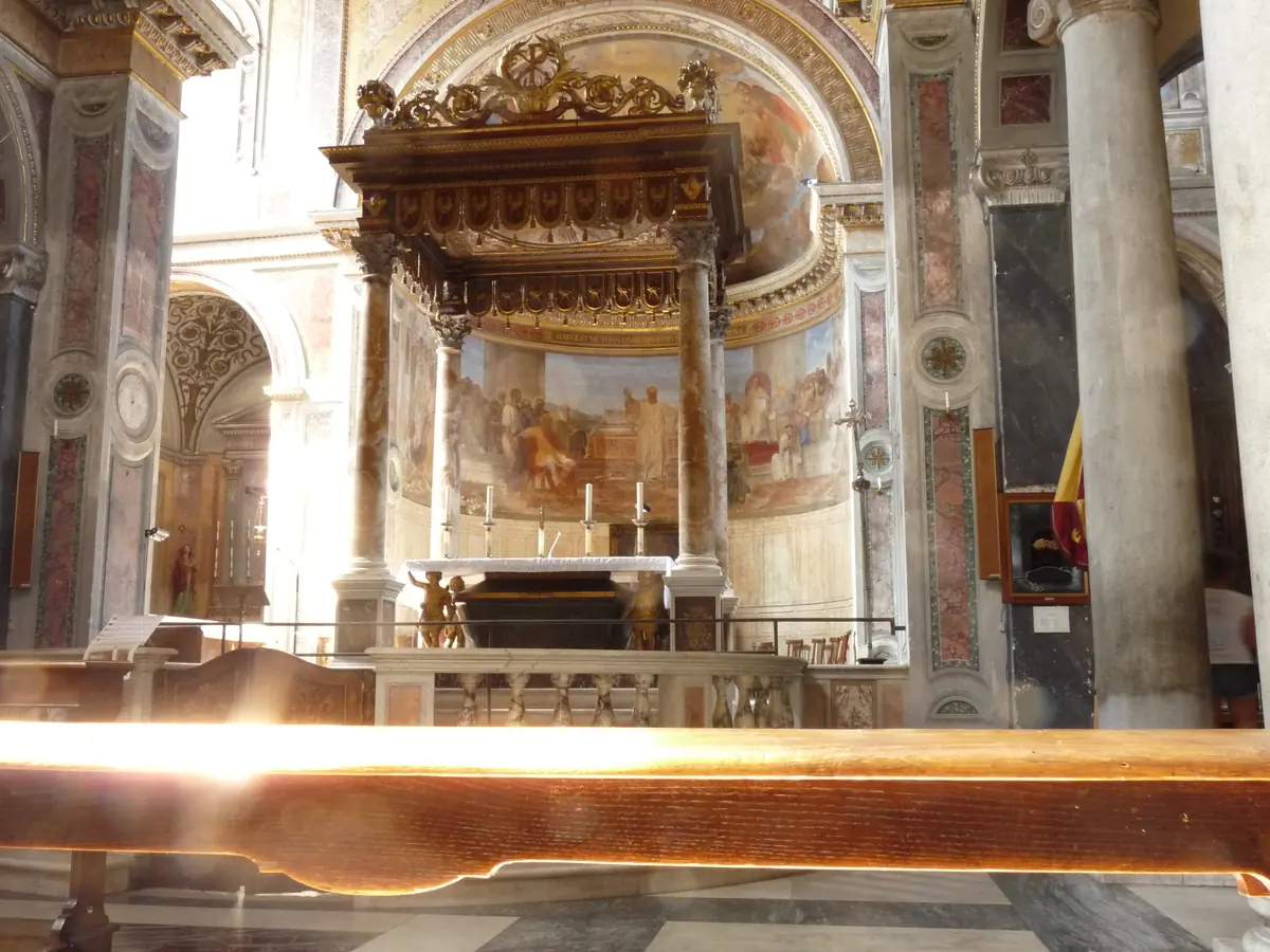 Die Apsis und der überdachte Hochaltar von San Nicola in Carcere mit einem Fresko in der Halbkuppel und Marmorsäulen an den Seiten