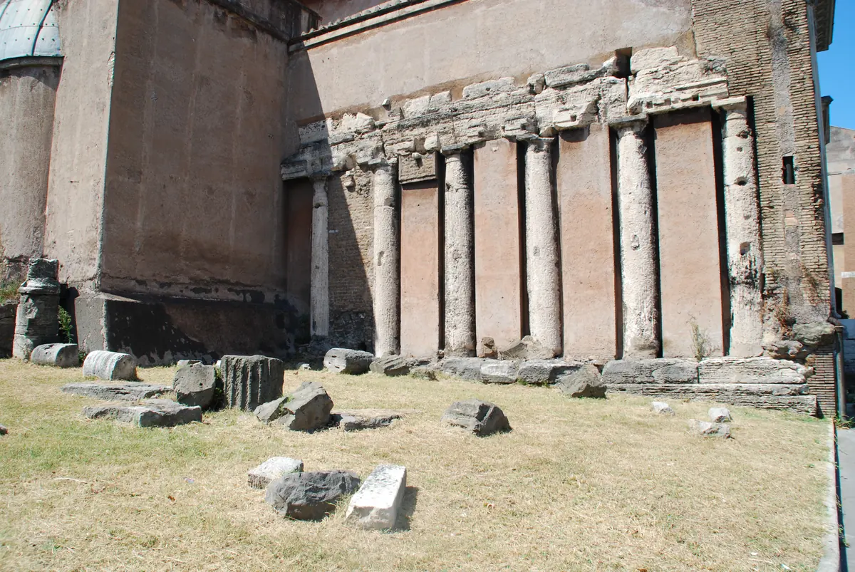 Die Überreste des südlichen Tempels des Forum Holitorium: ein Abschnitt antiker Mauer mit einer Reihe von Halbsäulen und am Boden liegenden Steinblöcken