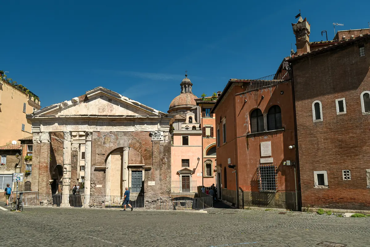 Portico d'Ottavia i Rom: en antik port med fronton af mursten og sten ved kanten af en brostensbelagt plads, med kirken Sant'Angelo in Pescheria indbygget